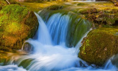 Dağdaki derede küçük bir şelale taşların üzerinden akıyor.