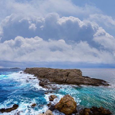 Mavi bulutlu gökyüzünün altındaki kayalık zümrüt deniz koyunda