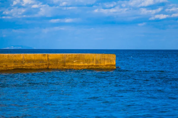 Каменный пирс в синем море — стоковое фото