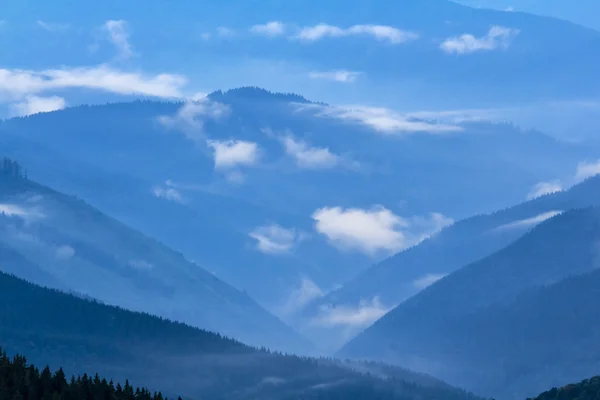 Silhouette spina dorsale di montagna in una nebbia blu — Foto Stock