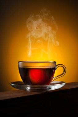 Ahşap masada bir bardak çay ve sarı arka ışık.