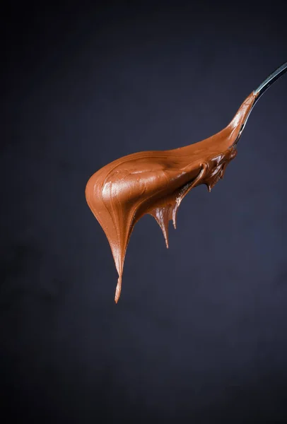 Krim Coklat Dalam Sendok Pada Latar Belakang Hitam — Stok Foto