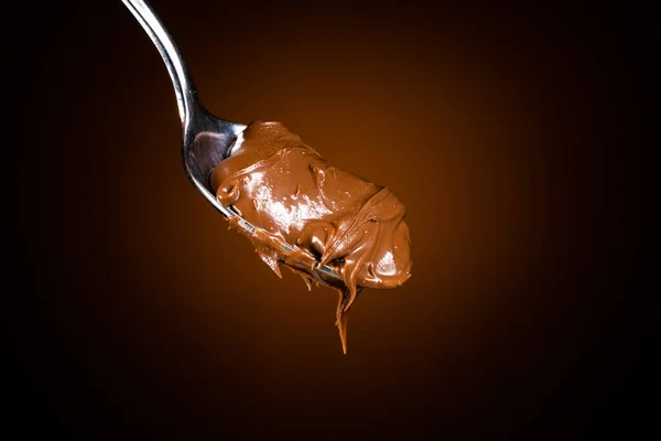 Krim Coklat Dalam Sendok Pada Latar Belakang Hitam — Stok Foto
