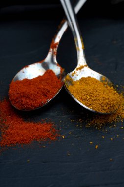 Siyah arka planda metal kaşıkta baharatlar