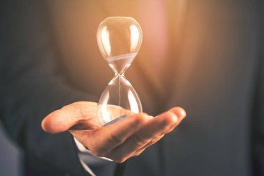 İş adamı kum saatini elinde tutuyor.