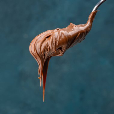 Eski bir arka planda kaşıkta kremalı çikolata.