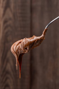 Tahta bir arka planda kaşıkta kremalı çikolata.