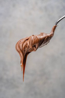 Eski bir arka planda kaşıkta kremalı çikolata.