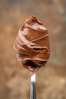 Eski bir arka planda kaşıkta kremalı çikolata.