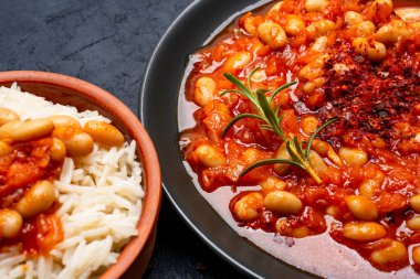 Siyah zemin üzerinde siyah tabakta pişmiş fasulye yemeği..