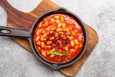 Eski arkaplanda pişirilmiş fasulye kabı dökme demir tavada..