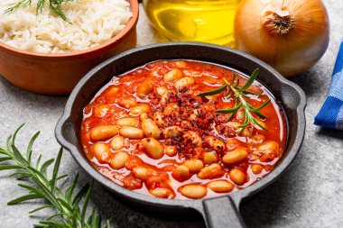 Eski arkaplanda pişirilmiş fasulye kabı dökme demir tavada..