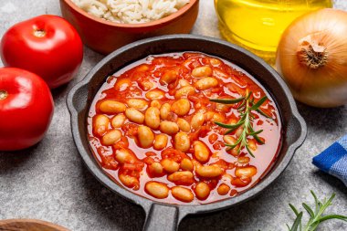 Eski arkaplanda pişirilmiş fasulye kabı dökme demir tavada..