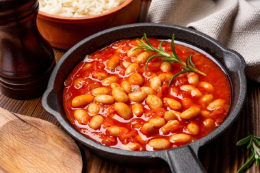 Ahşap zeminde pişirilmiş fasulye kabı dökme demir tavada..