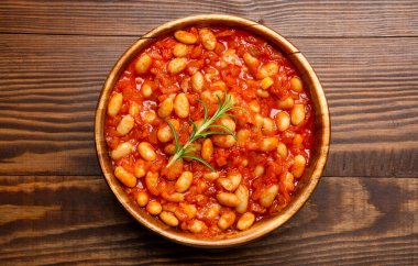 Ahşap arka planda ahşap kasede pişirilmiş fasulye yemeği..