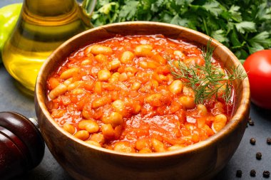 Siyah arka planda, ahşap kasede pişirilmiş fasulye yemeği..