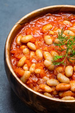 Siyah arka planda, ahşap kasede pişirilmiş fasulye yemeği..