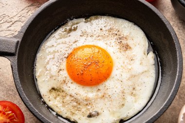 Bir yumurta dökme demir bir tavada, eski taş arka planda pişirilmiş.