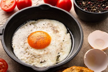 Bir yumurta dökme demir bir tavada, eski taş arka planda pişirilmiş.