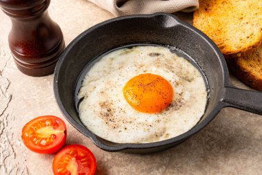 Bir yumurta dökme demir bir tavada, eski taş arka planda pişirilmiş.