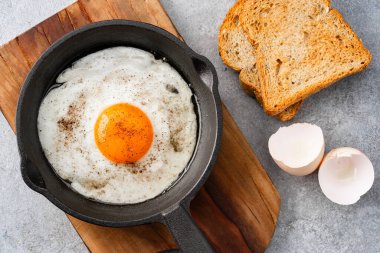 Bir yumurta dökme demir bir tavada, eski taş arka planda pişirilmiş.