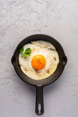Bir yumurta dökme demir bir tavada, eski taş arka planda pişirilmiş.