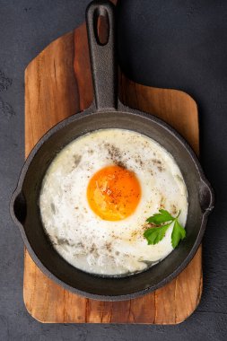 One egg cooked in a cast iron pan on black stone background