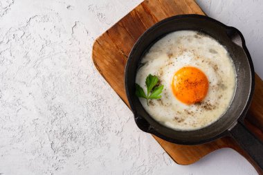 Bir yumurta dökme demir bir tavada, eski taş arka planda pişirilmiş.