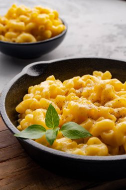 Gri taş arka planda lezzetli bir tavada peynirli makarna