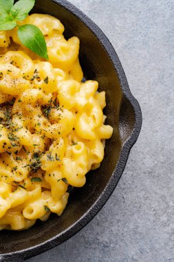 Gri taş arka planda lezzetli bir tavada peynirli makarna