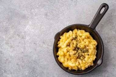 Gri taş arka planda lezzetli bir tavada peynirli makarna