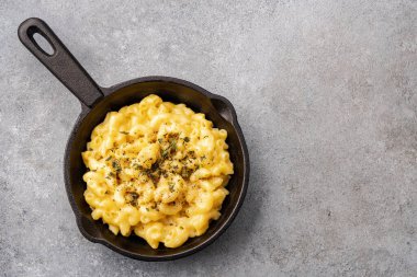 Gri taş arka planda lezzetli bir tavada peynirli makarna