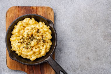 Gri taş arka planda lezzetli bir tavada peynirli makarna