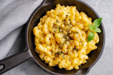 Gri taş arka planda lezzetli bir tavada peynirli makarna