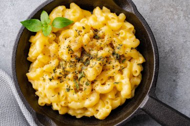 Gri taş arka planda lezzetli bir tavada peynirli makarna
