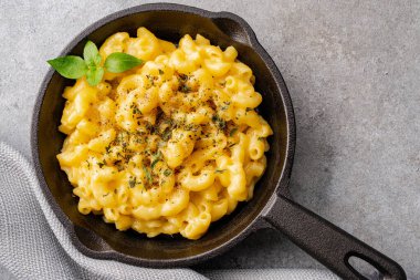 Gri taş arka planda lezzetli bir tavada peynirli makarna