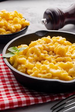 Gri taş arka planda lezzetli bir tavada peynirli makarna