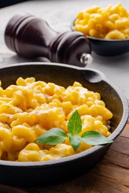Gri taş arka planda lezzetli bir tavada peynirli makarna