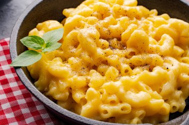 Gri taş arka planda lezzetli bir tavada peynirli makarna