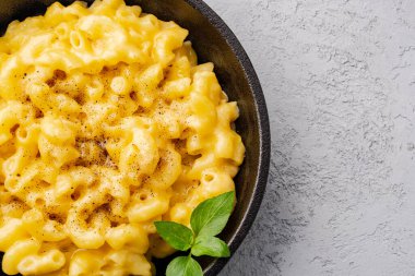 Gri taş arka planda lezzetli bir tavada peynirli makarna