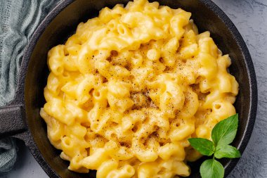 Gri taş arka planda lezzetli bir tavada peynirli makarna