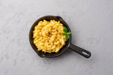 Gri taş arka planda lezzetli bir tavada peynirli makarna