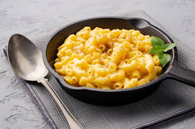 Gri taş arka planda lezzetli bir tavada peynirli makarna