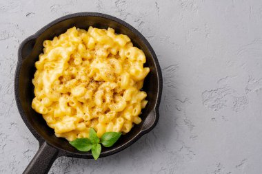 Gri taş arka planda lezzetli bir tavada peynirli makarna
