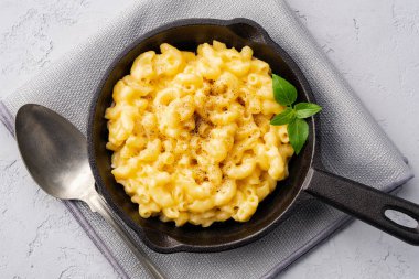 Gri taş arka planda lezzetli bir tavada peynirli makarna