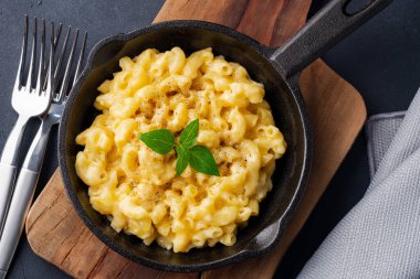 Siyah taş arka planda lezzetli bir tavada peynirli makarna.