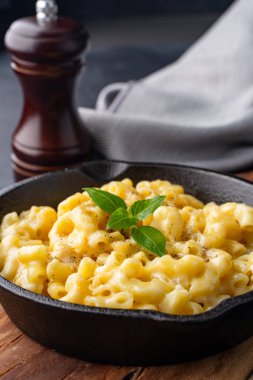 Siyah taş arka planda lezzetli bir tavada peynirli makarna.