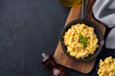 Siyah taş arka planda lezzetli bir tavada peynirli makarna.