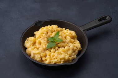 Siyah taş arka planda lezzetli bir tavada peynirli makarna.