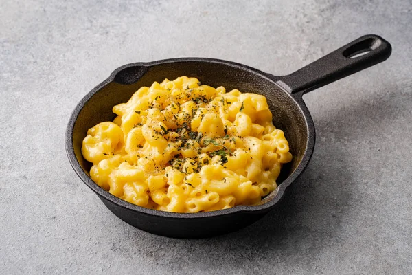 Gri taş arka planda lezzetli bir tavada peynirli makarna